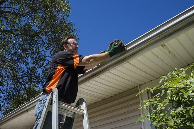 a professional repairing a leaking gutter to prevent water damage in Clark